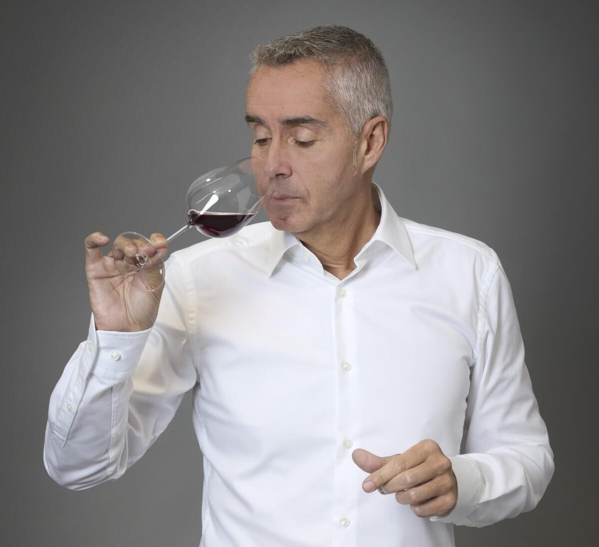 Damien Delattre, expert en dégustation, analyse les arômes d'un grand cru de Bourgogne, le nez dans un verre de vin rouge.